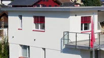 Aufgestocktes Wohnhaus mit roten Storen