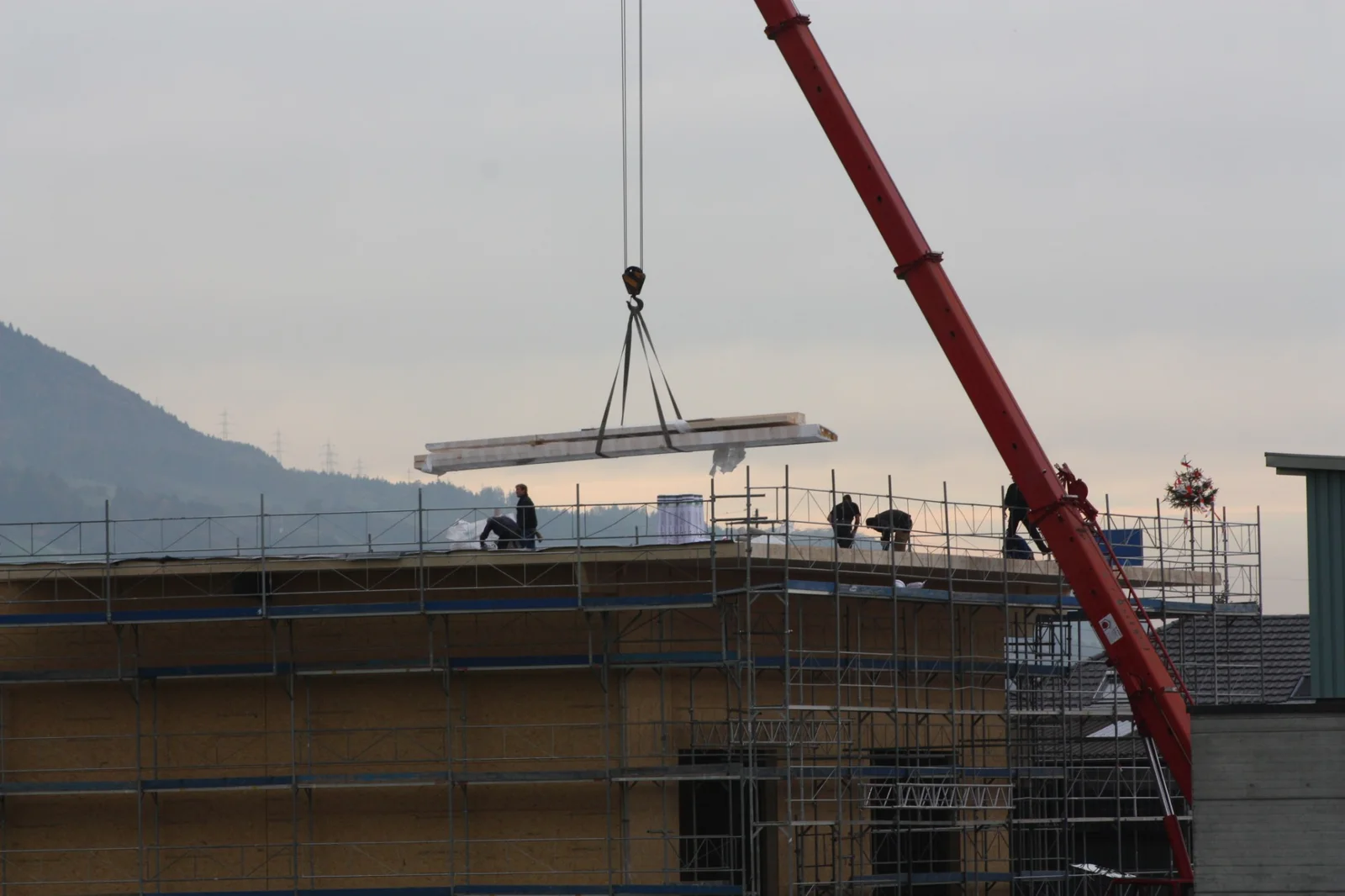 Kran hebt Holzelemente auf einen Neubau
