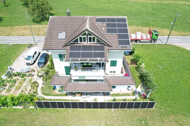 Photovoltaikanlage auf Dach und Gartenzaun eines Mehrfamilienhauses