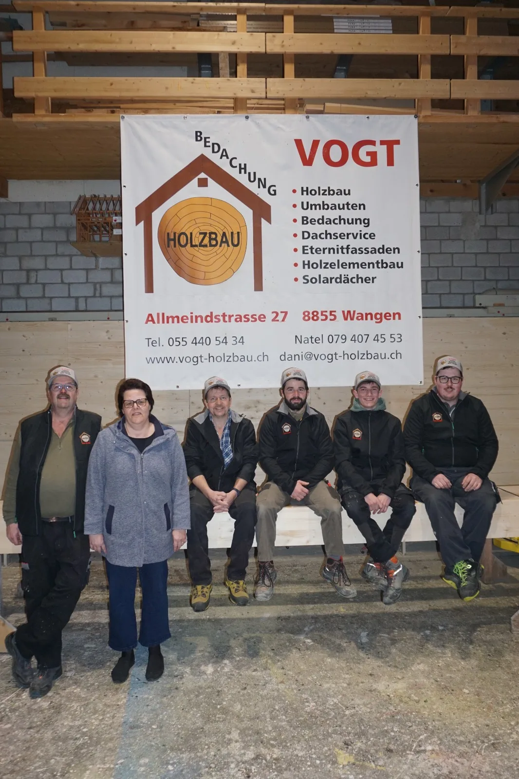 Das Team der D. Vogt Holzbau GmbH vor dem Firmenbanner